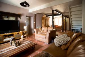 uma sala de estar com um sofá e uma televisão de ecrã plano em Maison du bois em Saint-Antoine