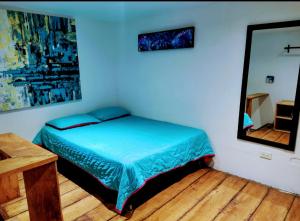 a bedroom with a blue bed and a mirror at Parrot House San Antonio in Cali