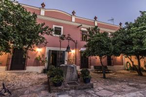 różowy budynek z drzewami przed nim w obiekcie Finca Villa Juan w mieście Ribera del Fresno