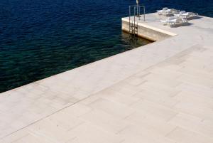 a dock with chairs and tables next to the water at Brna Three-room apartment near the beach-Zen in Brna