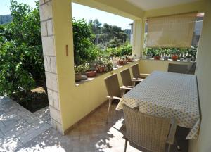 a table and chairs on a balcony with a table and a window at Brna Three-room apartment near the beach-Zen in Brna