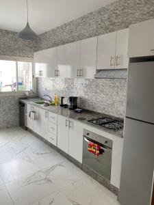 una cocina con armarios blancos y electrodomésticos de acero inoxidable en Lovely 4-bedroom condo with pool, en Rabat
