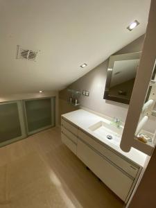 ein Badezimmer mit einem weißen Waschbecken und einem Spiegel in der Unterkunft Casa en la playa in Pobra do Caramiñal
