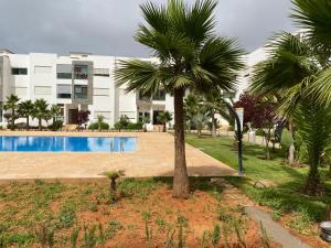 una palmera y una piscina frente a un edificio en Lovely 4-bedroom condo with pool, en Rabat