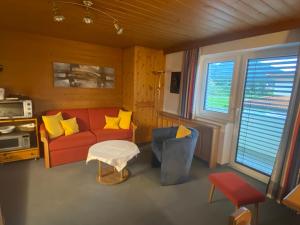 a living room with a red couch and yellow pillows at Haus am Achengrund in Kössen