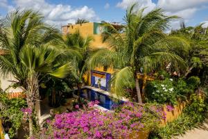 a resort with palm trees and purple flowers at Pousada Dharma in Jericoacoara