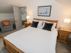 a bedroom with a large white bed and a chair at Homestead Cottage in Shipston on Stour