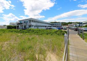 a building on a beach next to a wooden boardwalk at On the Beach Motel in Old Orchard Beach