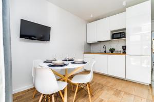 a kitchen with white cabinets and a table and chairs at Flatbook Apartamenty - Mikoszewo Wczasowa in Mikoszewo
