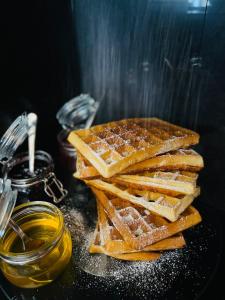 a pile of waffles sitting on a table with honey at Royal Road Residence in Prague