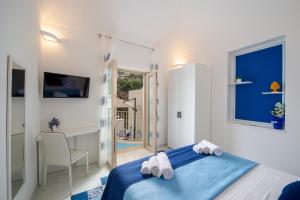 um quarto branco com uma cama azul e uma secretária em Residence Buonocore em Amalfi