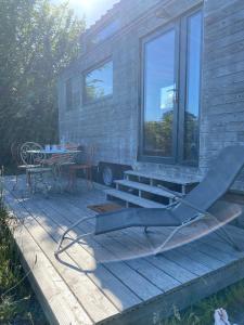 a house with a deck with a table and a chair at tiny house du poulloguer in Prat