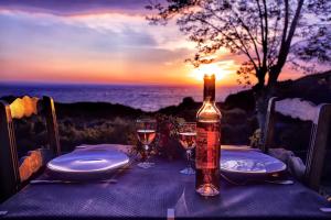 a bottle of wine sitting on a table with glasses at Auberge Ferayola in Galeria