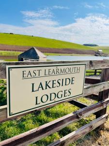 una señal en una valla que lee alojamientos de fugas de lemnotide este en East Learmouth Lakeside Lodges, en Cornhill-on-tweed