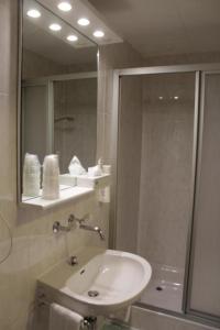 a bathroom with a sink, mirror, and bathtub at Hostellerie du XVI Siècle in Nyon