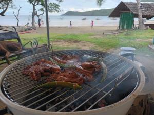 a grill with meat and peppers on a beach at Tupi's Beachfront Minihouse in Bacungan