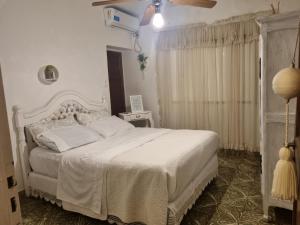 a bedroom with a white bed and a ceiling fan at White House - Hospedaje con Desayuno in La Rioja