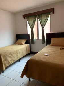 1 dormitorio con 2 camas y ventana en Casa a 5 minutos de los parques del IRTRA, en Pucá