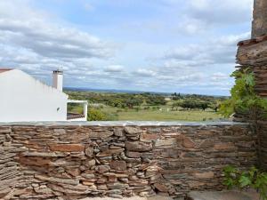 a stone wall with a view of a field at Casa Torta in Outeiro +5 photos