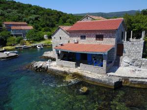 a house on a dock in a body of water at Beachfront villa Kakrc in Tivat