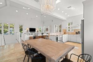 una grande cucina bianca con tavolo e sedie in legno di Ocean Serenade a Rosemary Beach