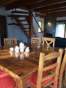 een houten tafel met stoelen en een grote houten tafel met kopjes bij Cabañas La Ufu in Las Golondrinas