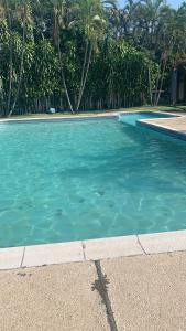 einen Pool mit blauem Wasser und Palmen in der Unterkunft Casa a 5 minutos de los parques del IRTRA in Pucá