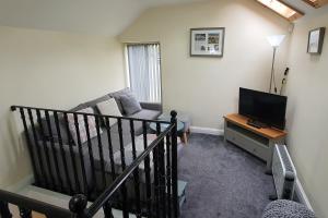 a living room with a couch and a television at Sandy's Barn, Foolow, Dogs Welcome in Foolow