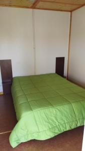 un letto in una camera con un piumone verde di Complexe Touristique La Montagne Limousine a Chamberet