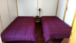 2 letti in una camera con lenzuola viola di Complexe Touristique La Montagne Limousine a Chamberet Altre 22 foto