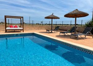 - une piscine avec 2 chaises longues et des parasols dans l'établissement Son Sea Villa, à Campos