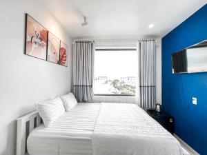 1 dormitorio con 1 cama blanca grande y pared azul en New Hotel en Rạch Giá