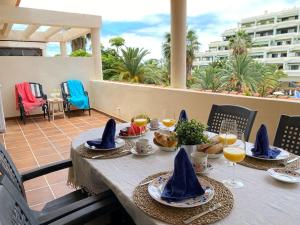 einen Tisch mit Essen und Weingläsern auf dem Balkon in der Unterkunft Luminoso apartamento con terraza y piscina in Puerto de la Cruz