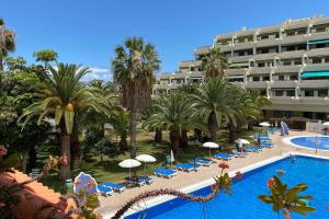a view of a hotel with a pool and palm trees at Luminoso apartamento con terraza y piscina in Puerto de la Cruz