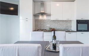 uma cozinha com armários brancos e uma mesa com copos de vinho em Cozy Apartment In Senj With Kitchen em Senj