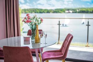 uma mesa com um vaso de flores e taças de vinho em Apartamenty Z Widokiem Na Mazury Jezioro Czos Sauna Jacuzzi em Mrągowo