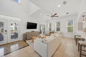 a living room with white furniture and a flat screen tv at Seacrest Getaway in Rosemary Beach