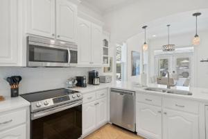 a kitchen with white cabinets and a stove top oven at Seacrest Getaway in Rosemary Beach
