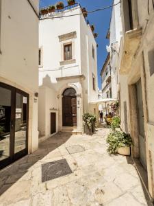 Une allée avec des bâtiments blancs et une porte marron dans l'établissement Domus San Giovanni, à Locorotondo