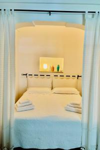 een slaapkamer met een bed met witte lakens en gordijnen bij Il Giardino degli Antichi Sapori in Ceglie Messapica