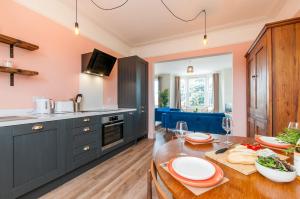 a kitchen with blue cabinets and a wooden table at Queen Palm Apartment - Margate - 3 mins walk to beach in Margate