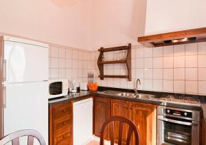 cocina con nevera blanca y armarios de madera en Son Sea Villa, en Campos