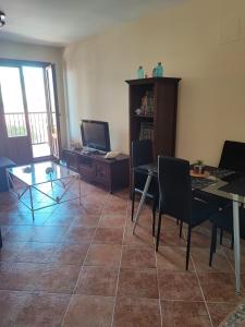 - un salon avec une table, des chaises et une télévision dans l'établissement Las encinas Golf y Playa, à Ayamonte