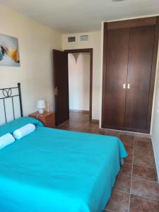 - une chambre avec un lit bleu et un placard dans l'établissement Las encinas Golf y Playa, à Ayamonte