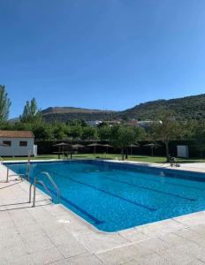 Una gran piscina azul con montañas al fondo. en Casa Nati, en Alfarnate
