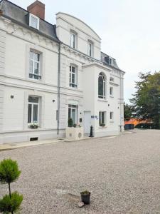uma grande casa branca com uma entrada de cascalho em Hôtel Échappée en Baie - Parking privé gratuit dont forfaits bornes électriques réservable em Saint-Valery-sur-Somme