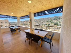 Habitación con mesas, sillas y ventana grande. en Villa Mira GuestHouse 2 - Downtown Central Amman - AL DIYRIH, en Amán