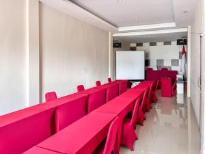 eine Reihe roter Stühle in einem Zimmer mit einem Whiteboard in der Unterkunft RedDoorz Plus @ Grand Tabona Hotel Ternate in Ternate