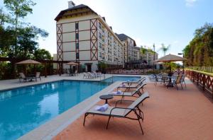 ein Hotelpool mit Tischen und Stühlen und ein Gebäude in der Unterkunft Quarto inteiro, Condomínio Vista Azul, Pedra Azul in Domingos Martins