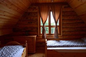 two beds in a log cabin bedroom with a window at Milanova koliba Zlatar in Nova Varoš